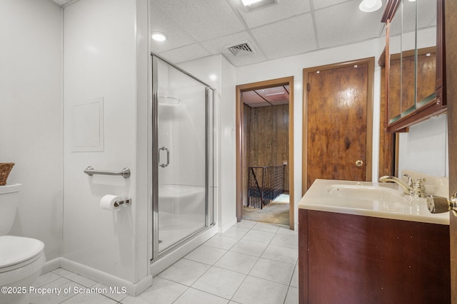 bathroom with vanity, a stall shower, a drop ceiling, tile patterned floors, and toilet