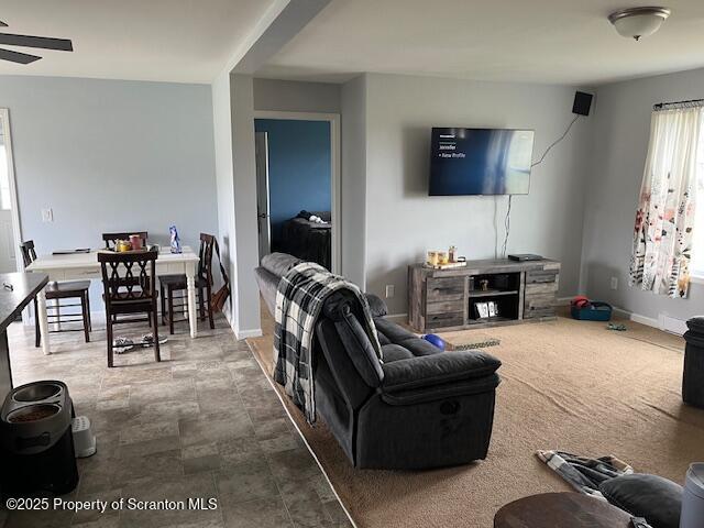living area featuring baseboards and ceiling fan