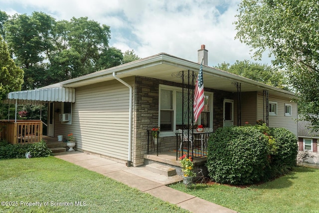 118 Howard St, Old Forge, PA 18518 - view of front of house with a porch, stone siding, a front yard, a chimney, and cooling unit