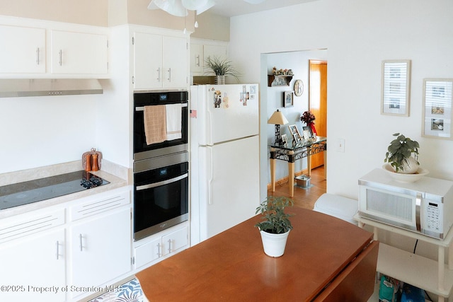 118 Howard St, Old Forge, PA 18518 - kitchen with white appliances, wall chimney exhaust hood, light countertops, ceiling fan, and white cabinets