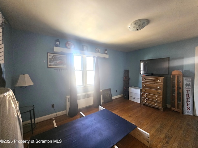 bedroom with radiator heating unit, wood finished floors, and baseboards