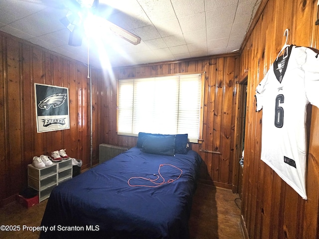 bedroom with radiator heating unit and wood walls