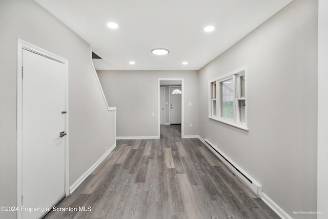 corridor with wood-type flooring and baseboard heating