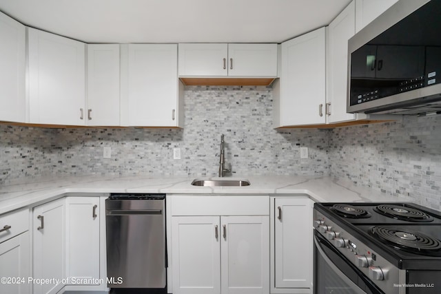 kitchen featuring backsplash, sink, appliances with stainless steel finishes, light stone counters, and white cabinetry