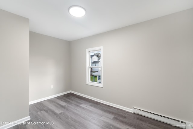 spare room featuring hardwood / wood-style flooring and a baseboard heating unit