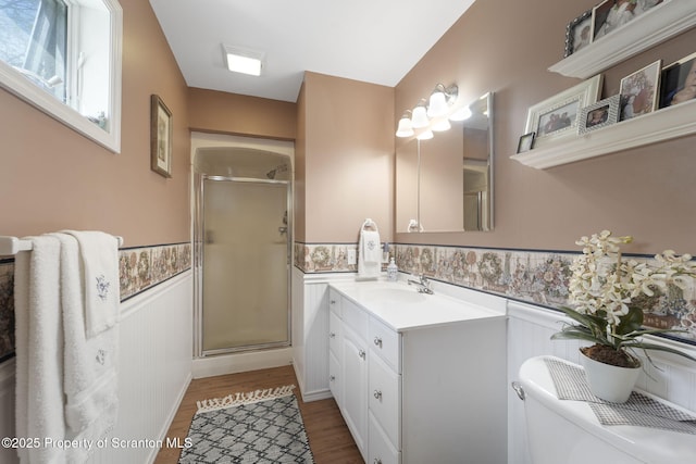 full bathroom featuring vanity, a shower stall, wainscoting, and wood finished floors