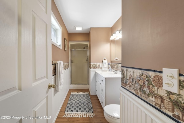 full bath featuring vanity, toilet, wood finished floors, and a stall shower