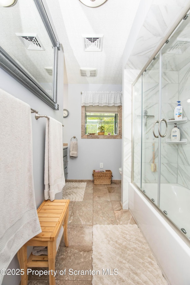 210 Willow Dr, Jefferson Twp, PA 18436 - bathroom featuring shower / bath combination with glass door, baseboards, stone finish floors, and toilet