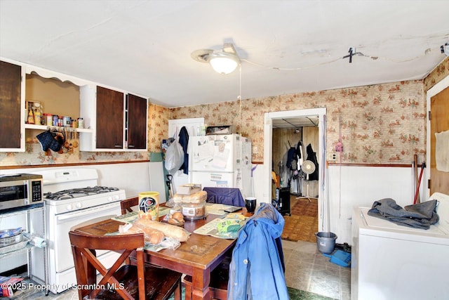 dining space with wainscoting and wallpapered walls