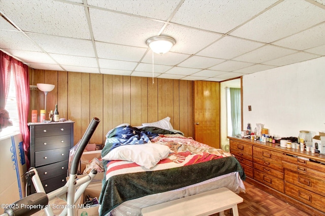 bedroom with a drop ceiling and wood walls