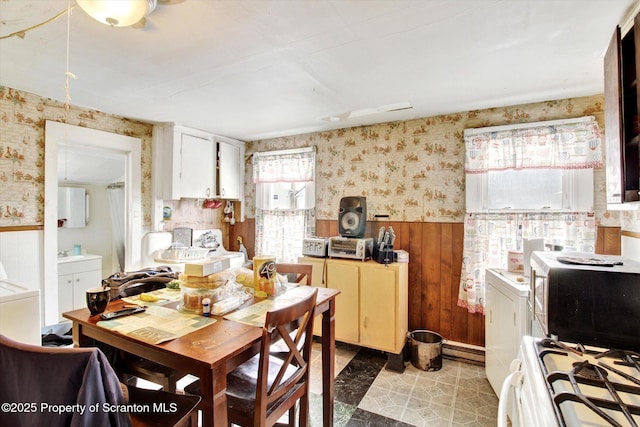 dining space featuring wainscoting and wallpapered walls