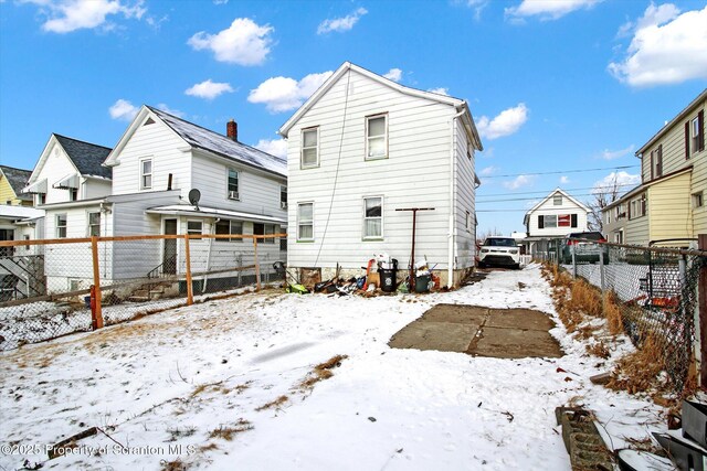 snow covered rear of property with a fenced backyard