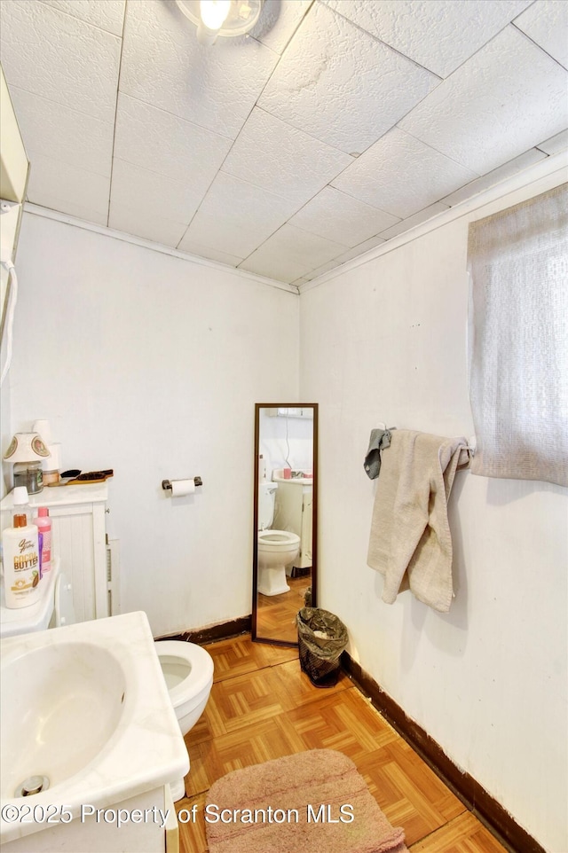 bathroom with toilet, baseboards, and a sink