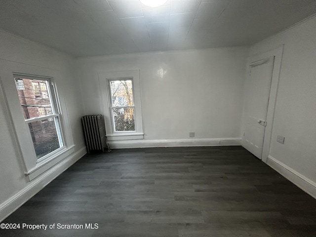 spare room featuring dark hardwood / wood-style floors and radiator