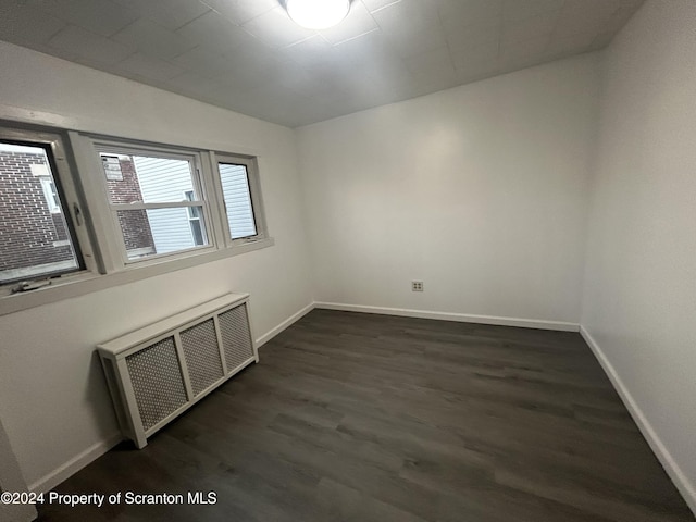 spare room with dark hardwood / wood-style floors and radiator