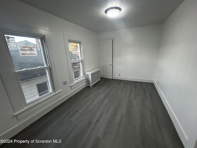 unfurnished room with dark hardwood / wood-style flooring and radiator heating unit