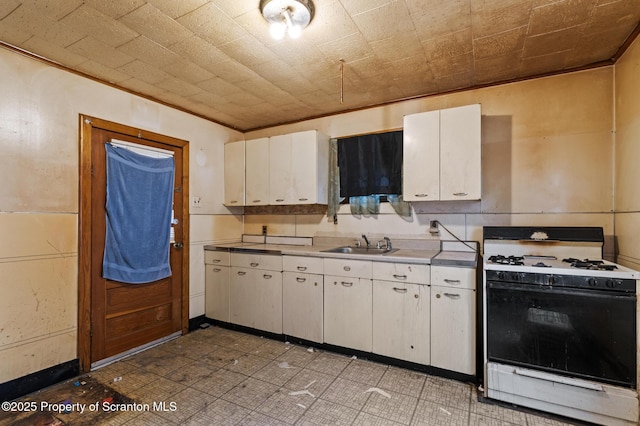 kitchen featuring white cabinets, white gas range oven, light countertops, and a sink