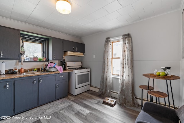 kitchen featuring light wood finished floors, blue cabinetry, under cabinet range hood, a baseboard radiator, and white range with gas cooktop
