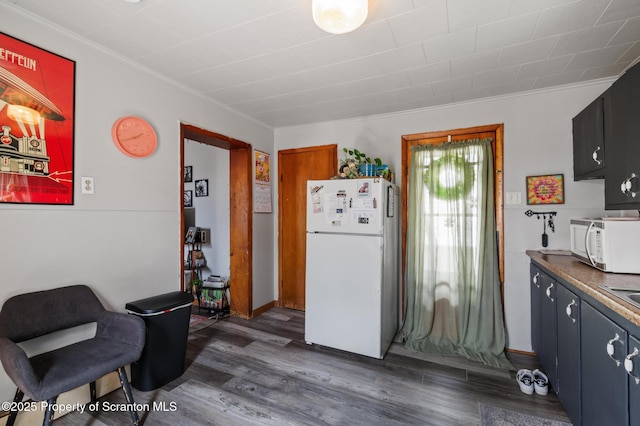 kitchen featuring crown molding, wood finished floors, and white appliances