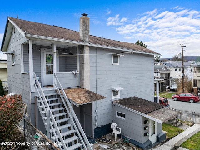 back of house with fence, a chimney, and stairs