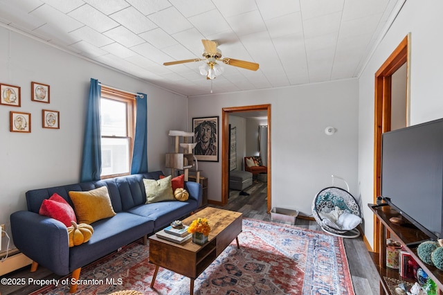 living area featuring a baseboard heating unit, wood finished floors, ceiling fan, and crown molding