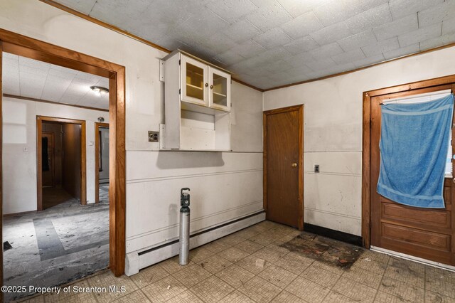 interior space with a baseboard radiator, ornamental molding, and tile patterned floors