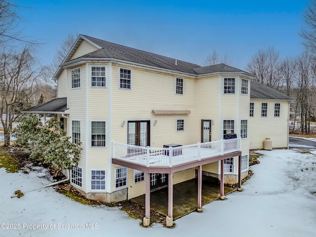 snow covered back of property with a deck