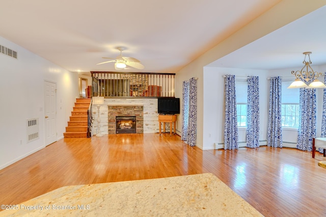 unfurnished living room featuring ceiling fan with notable chandelier, a fireplace, wood finished floors, and visible vents