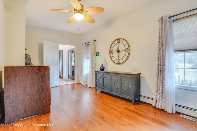 interior space with a baseboard heating unit and wood finished floors