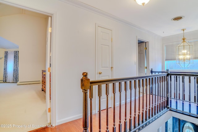 hallway featuring a chandelier, an upstairs landing, visible vents, baseboards, and ornamental molding