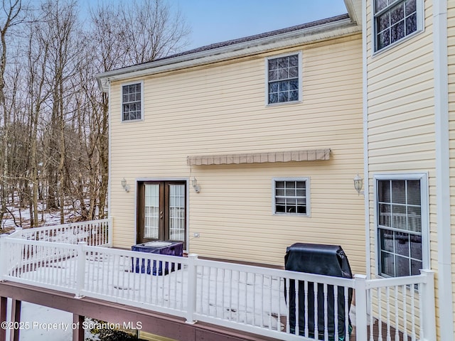 snow covered rear of property with a wooden deck