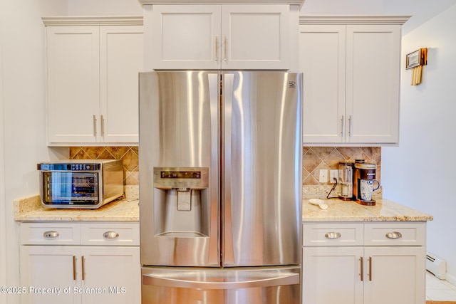 kitchen with light stone countertops, a toaster, a baseboard heating unit, stainless steel fridge with ice dispenser, and decorative backsplash