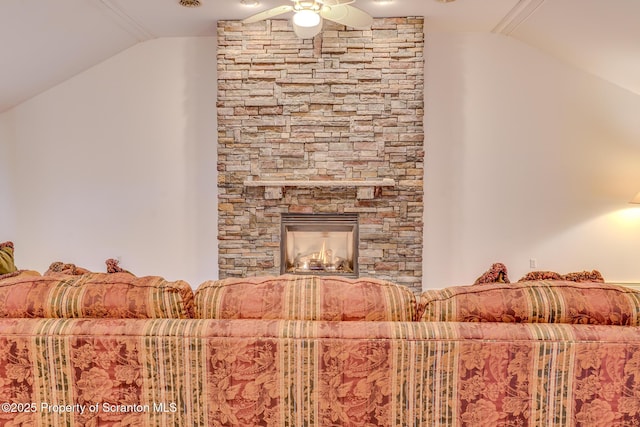 living area featuring ceiling fan, vaulted ceiling, and a stone fireplace