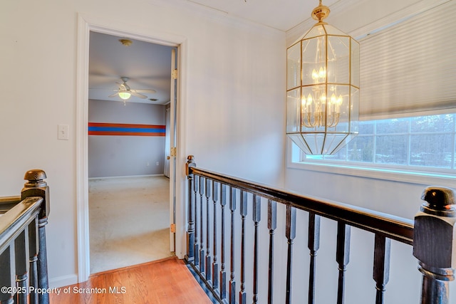 hallway featuring baseboards, a notable chandelier, and light wood finished floors