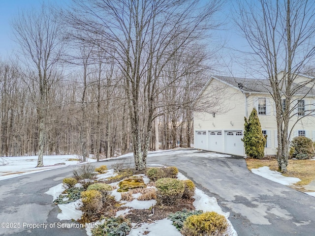 view of snowy exterior featuring a garage and aphalt driveway