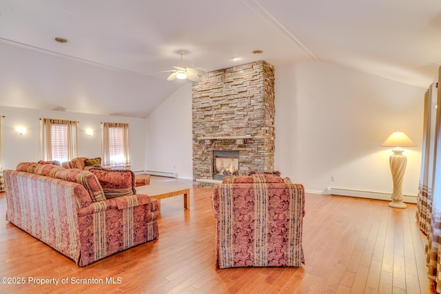 living room with a baseboard heating unit, vaulted ceiling, a fireplace, and light wood-style flooring