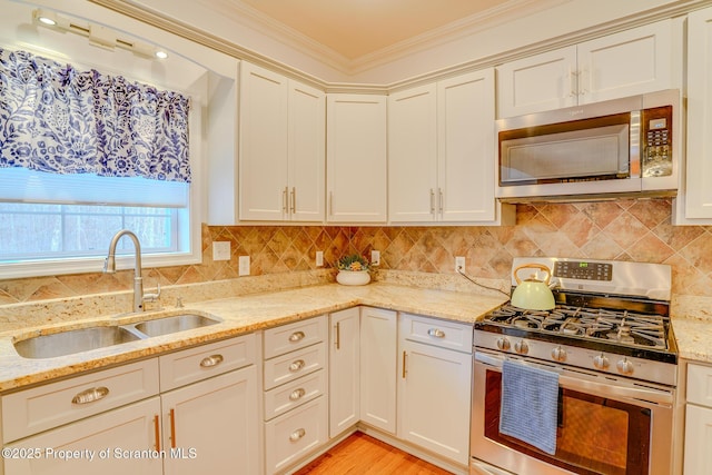 kitchen with stainless steel appliances, crown molding, a sink, and backsplash