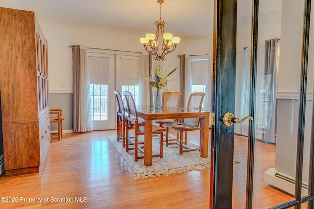 dining area featuring a baseboard radiator, crown molding, light wood-style flooring, and an inviting chandelier