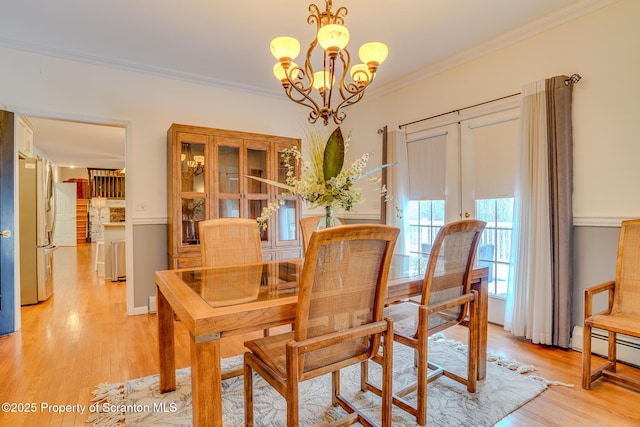 dining area featuring a notable chandelier, light wood-type flooring, and crown molding