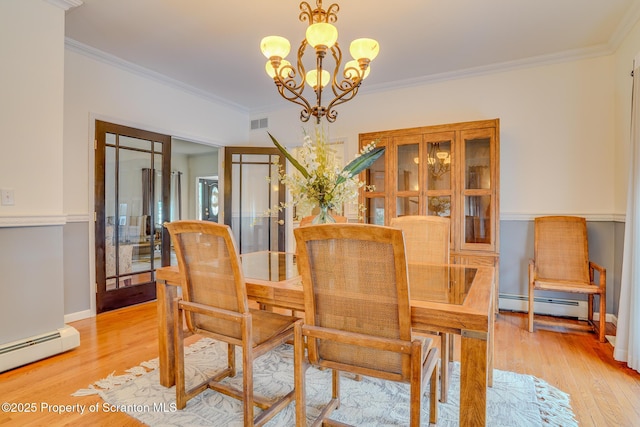 dining room featuring light wood finished floors, ornamental molding, baseboard heating, and an inviting chandelier