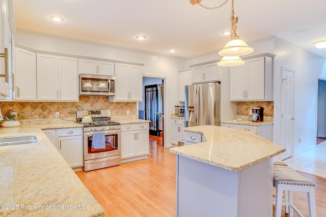 kitchen with light wood-style flooring, a kitchen island, light stone counters, a breakfast bar area, and stainless steel appliances