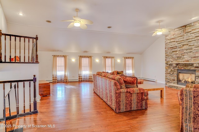 living room featuring ceiling fan, a fireplace, and light wood-style floors