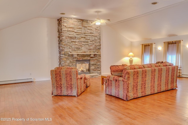 living room with vaulted ceiling, a stone fireplace, a baseboard radiator, and wood finished floors