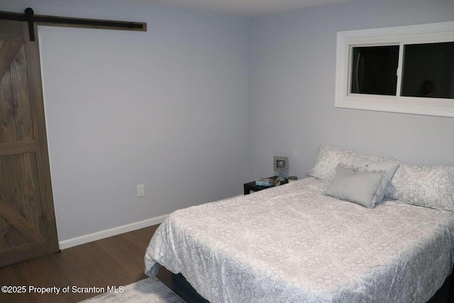 bedroom with a barn door and dark wood-type flooring