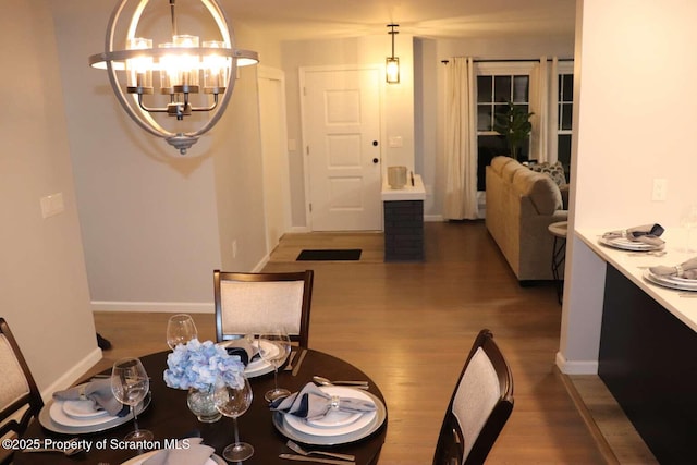 dining area with dark wood-type flooring and a notable chandelier