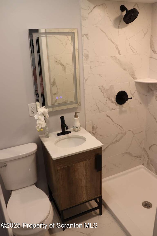 bathroom featuring vanity, tiled shower, and toilet