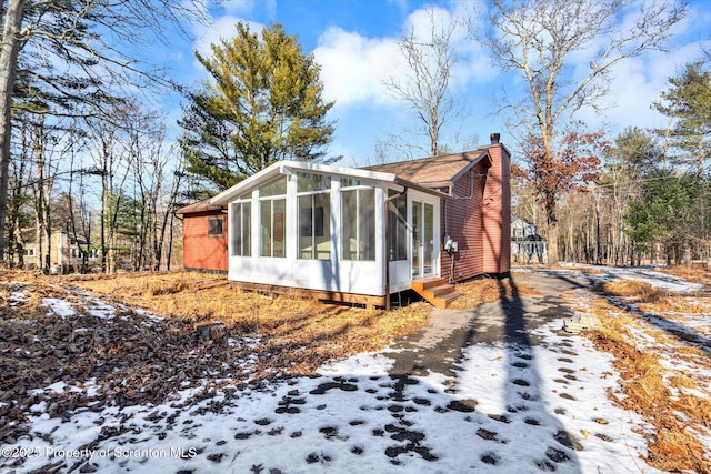 snow covered property with a sunroom