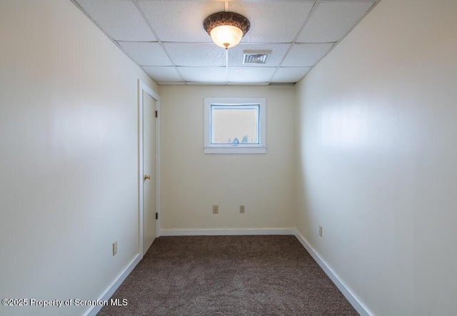 spare room with a paneled ceiling, visible vents, carpet floors, and baseboards