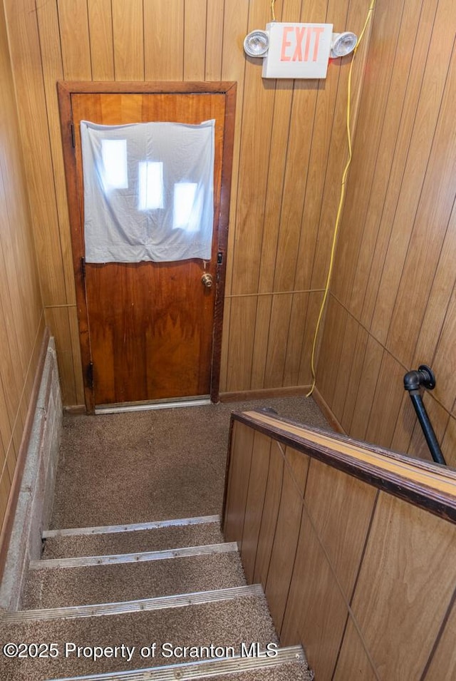 staircase featuring wooden walls