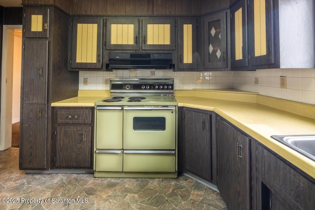 kitchen featuring ventilation hood, double oven range, backsplash, and light countertops